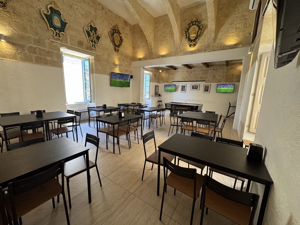 The indoor hall with tables and several TVs showing live sports